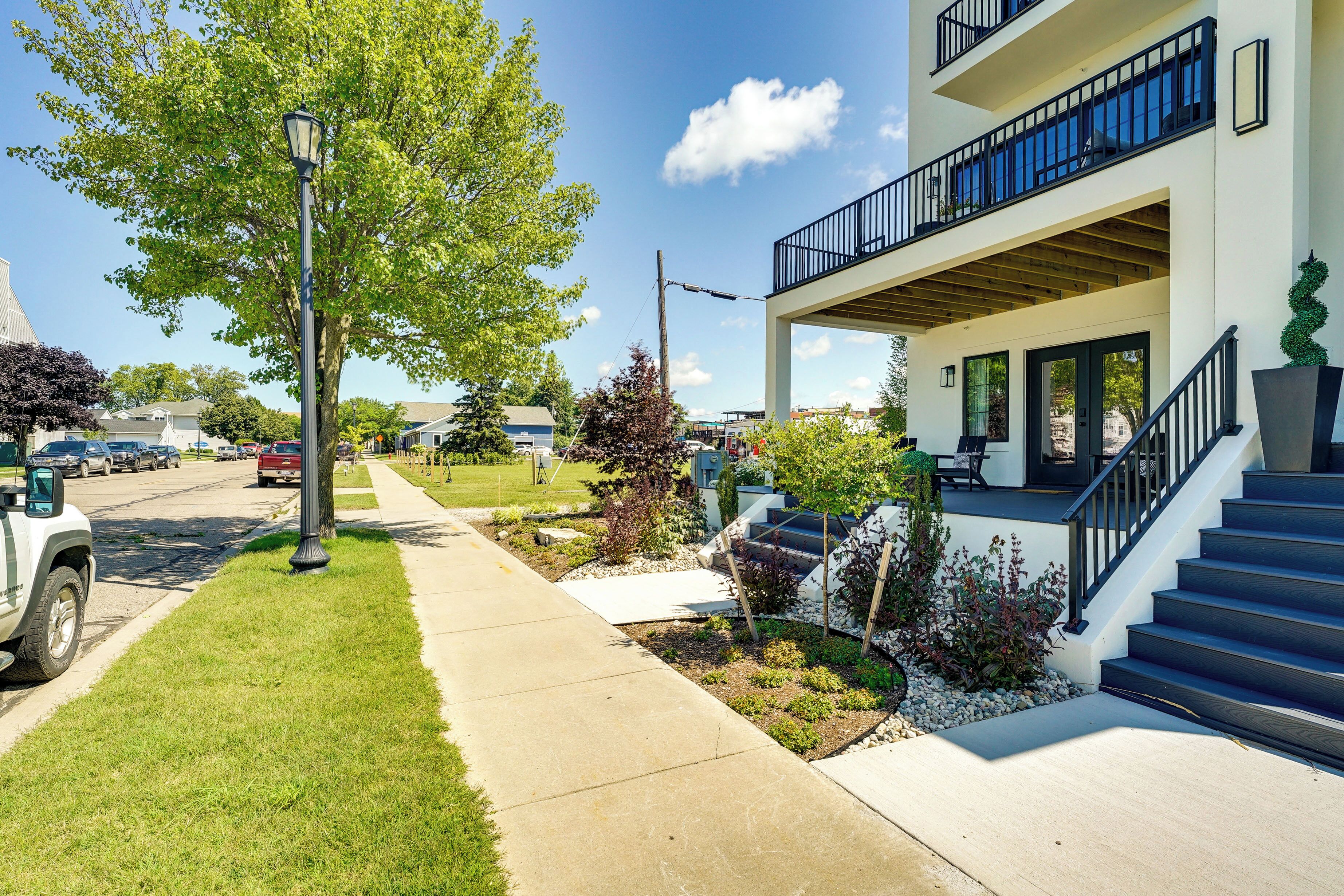 A modern two-story building with a balcony, a concrete pathway, and a well-maintained lawn.