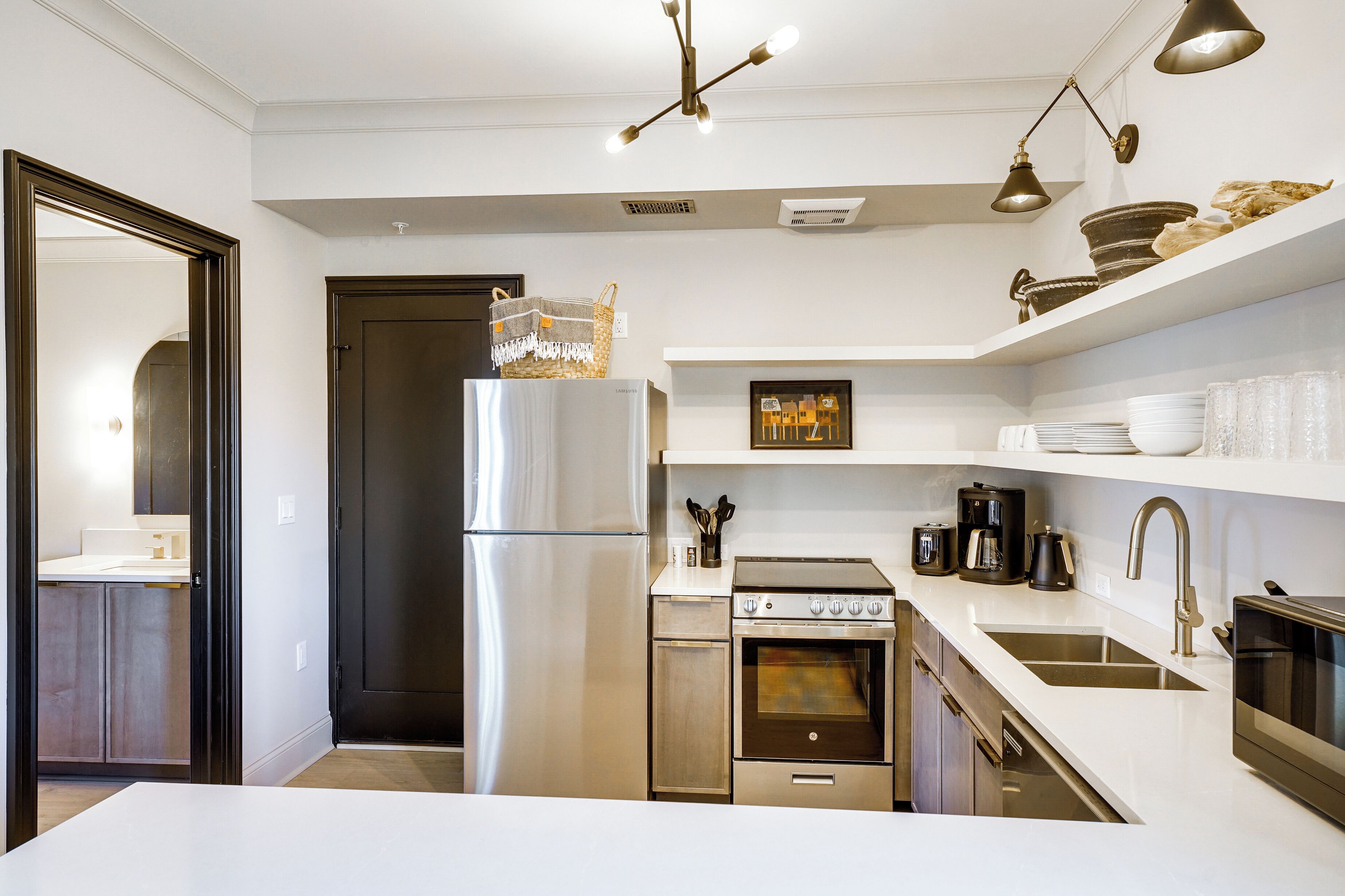 A modern kitchen with stainless steel appliances, white countertops, and a built-in oven.