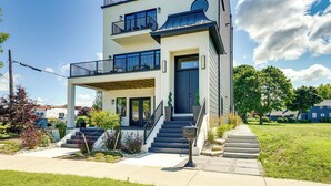 A modern two-story house with a covered front porch, a staircase leading to the entrance, and a well-maintained lawn.