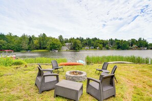 Un patio junto al lago con muebles de mimbre, una fogata y una canoa.