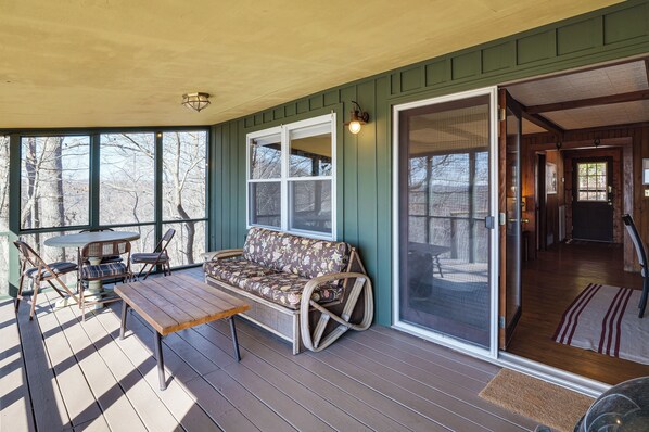 A covered porch with a wooden bench, a cushioned sofa, and a table.