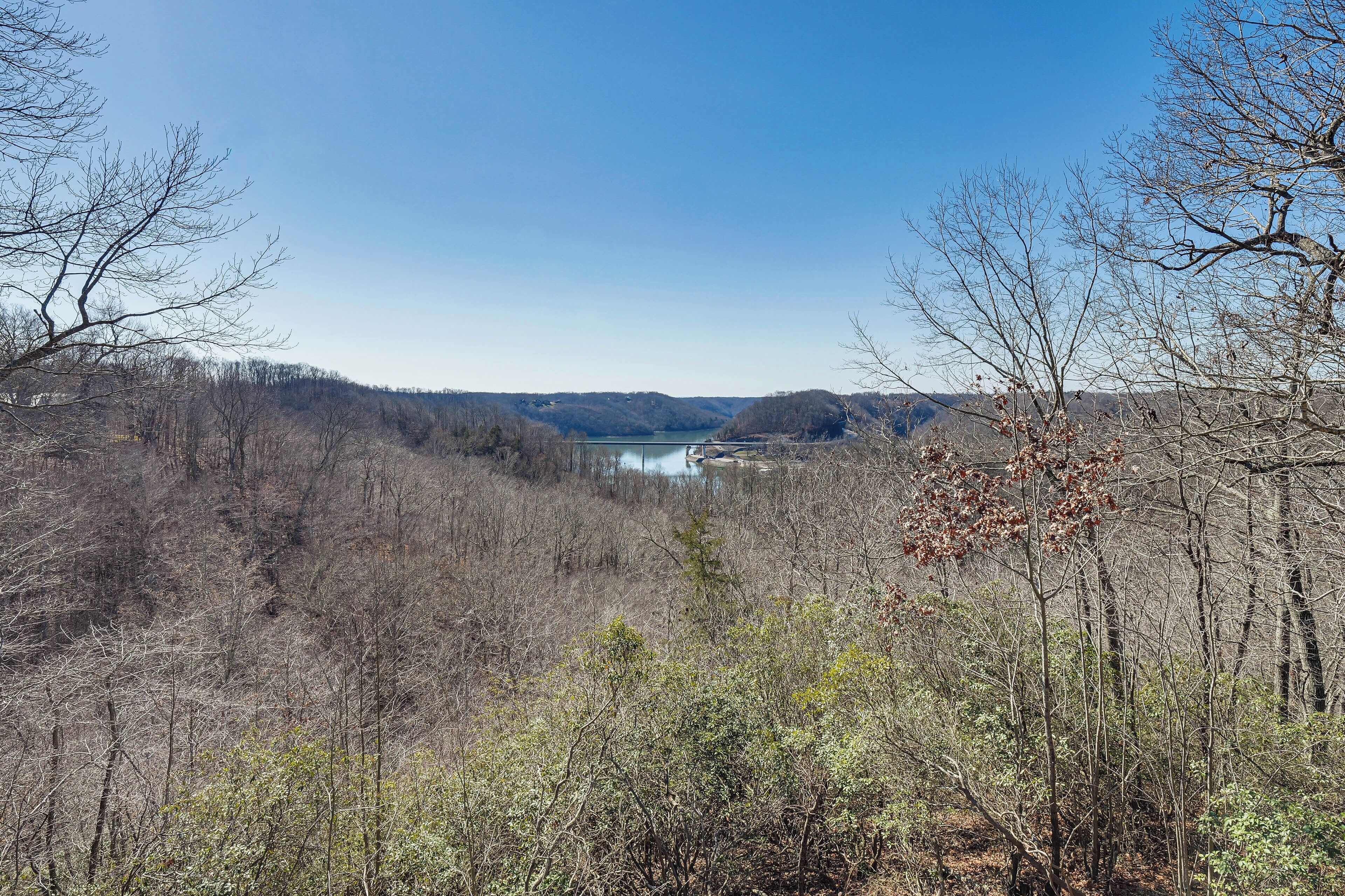 A natural landscape with a lake, surrounded by trees and hills.