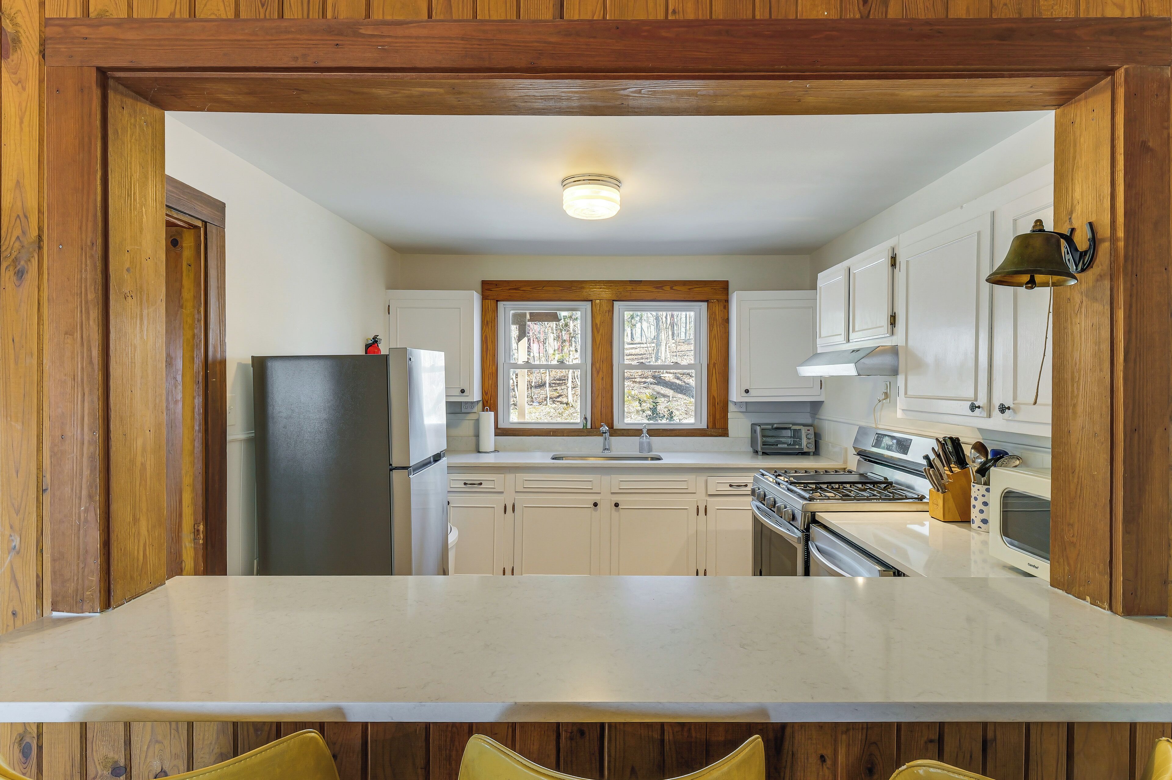 A kitchen with wooden cabinets, a central island, a refrigerator, a stove, and a microwave.