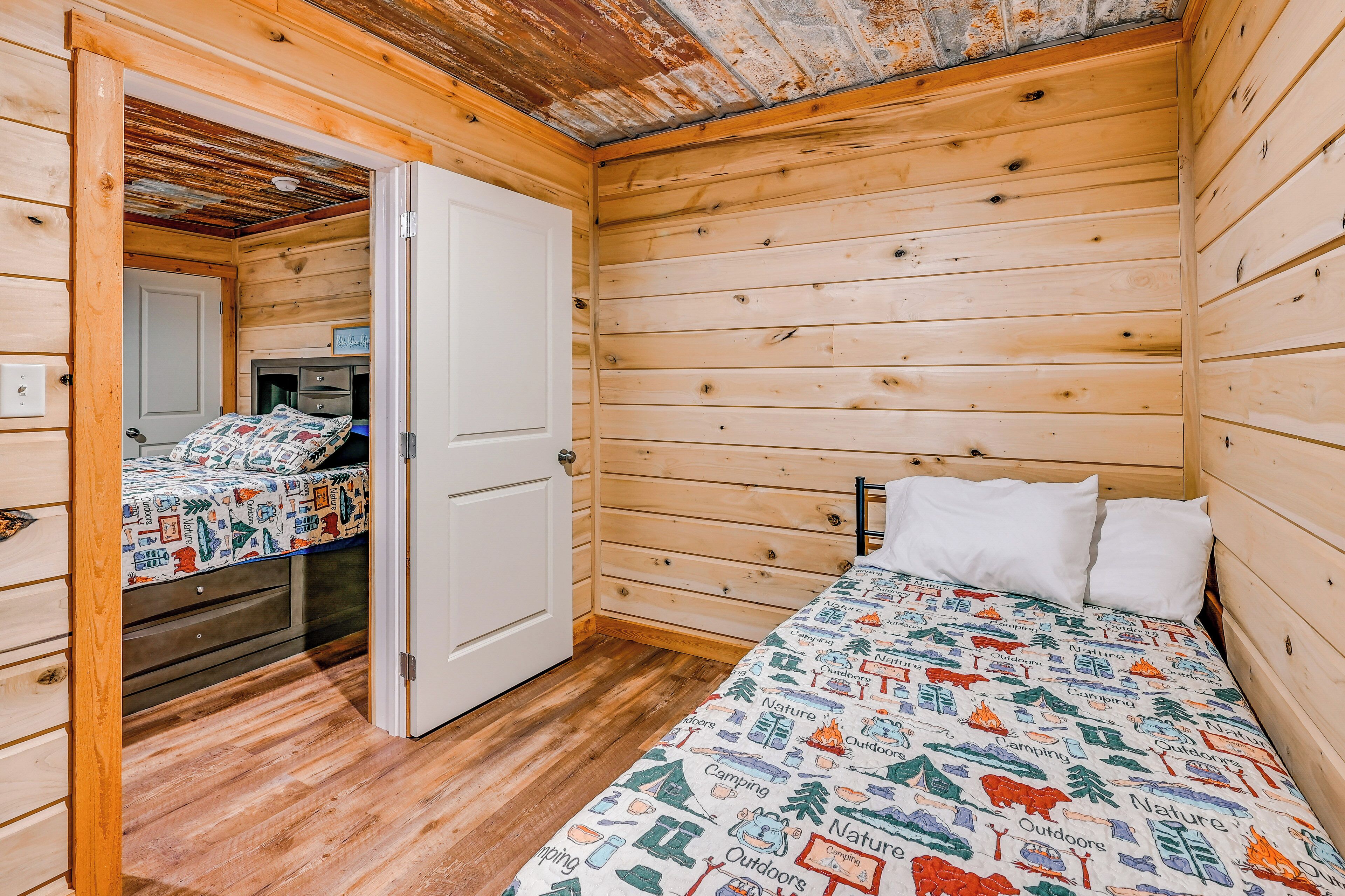 A wooden cabin room with a bed, a door, and a small desk.