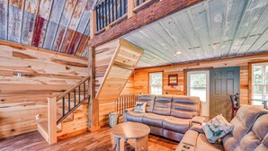 A log cabin interior with a wooden staircase, leather sofas, and a round coffee table. - Kentucky Cabin Retreat w/ Covered Porch & Views (Lewisburg)