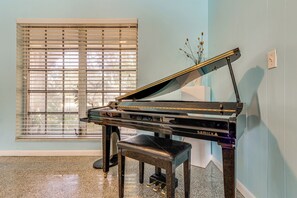A grand piano in a room with light blue walls and a window with blinds. - Waterfront Vero Beach Home w/ Pool & Boat Dock! (Vero Beach)