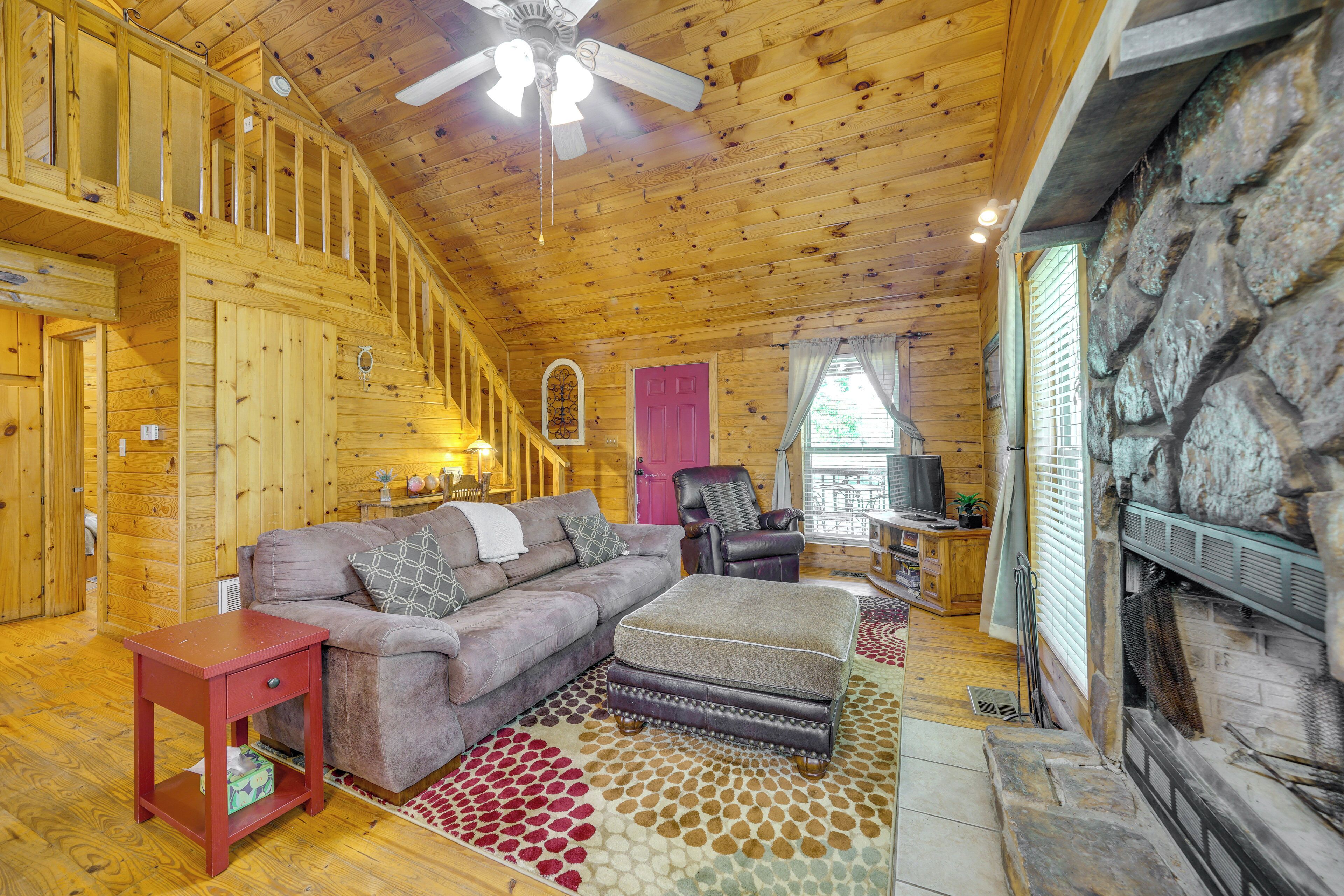 A wooden cabin interior with a sofa, ottoman, and a small red side table.
