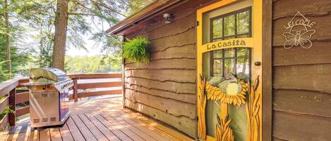 Une cabane en bois avec une terrasse, un barbecue et une porte portant l’inscription « La Casita ».