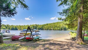 A lakeside campsite with canoes and a bench. - Inlet Lakefront Home: Private Dock & Beach Access! (Inlet)