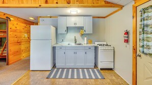 A compact kitchen with light blue cabinets, a white refrigerator, and a stove. - Inlet Lakefront Home: Private Dock & Beach Access! (Inlet)