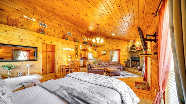 Ein gemütliches Blockhaus mit einem großen Bett, einem Kamin und einem Essbereich.