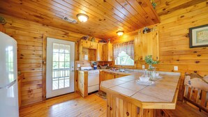 Ein Holzblockhaus-Interieur mit Küche, Essbereich und einem großen Fenster.