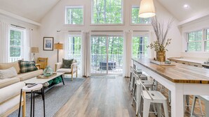 A spacious kitchen with a high ceiling, large windows, and a central island.