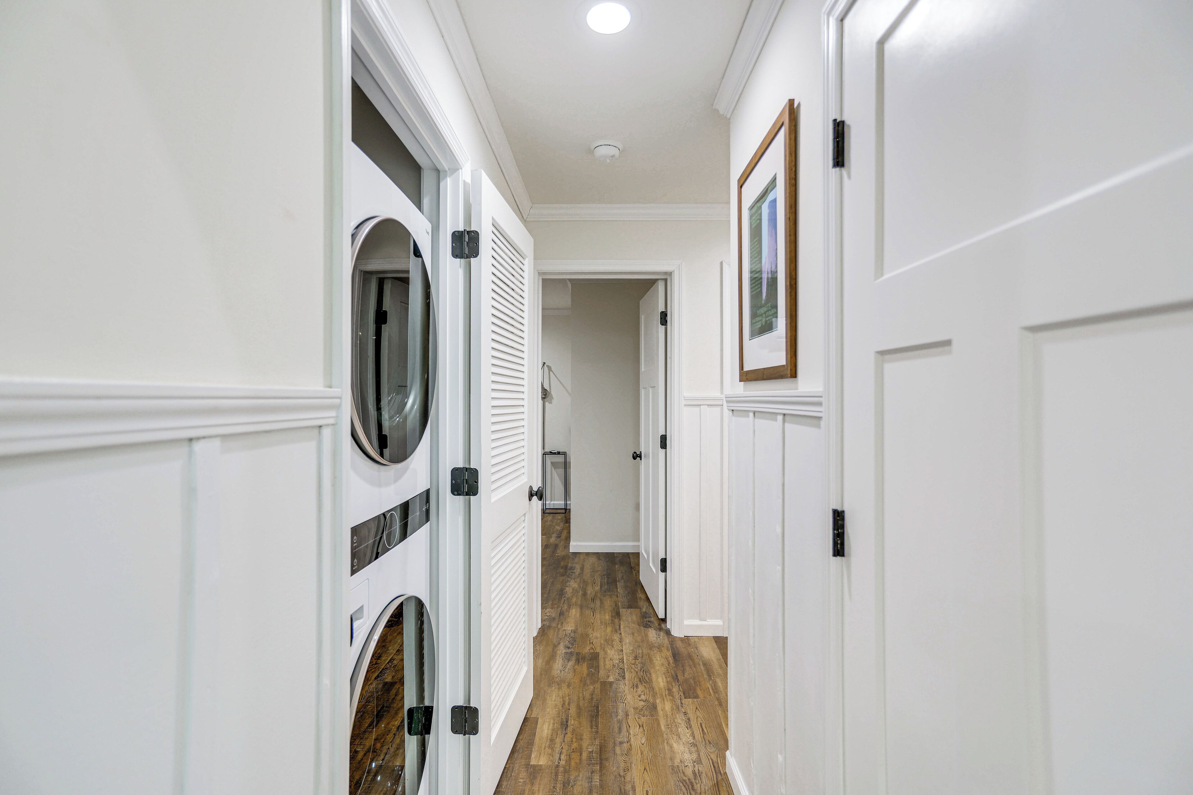 A hallway with a laundry room on the left, featuring a dryer and a washing machine.