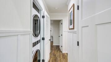 A hallway with a laundry room on the left, featuring a dryer and a washing machine.