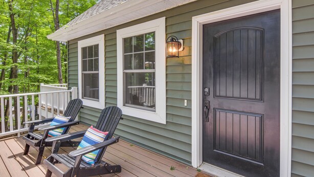 A wooden deck with two Adirondack chairs and a dark front door. - Treasure Lake Home w/ Deck: Walk to Bimini Lake! (DuBois)
