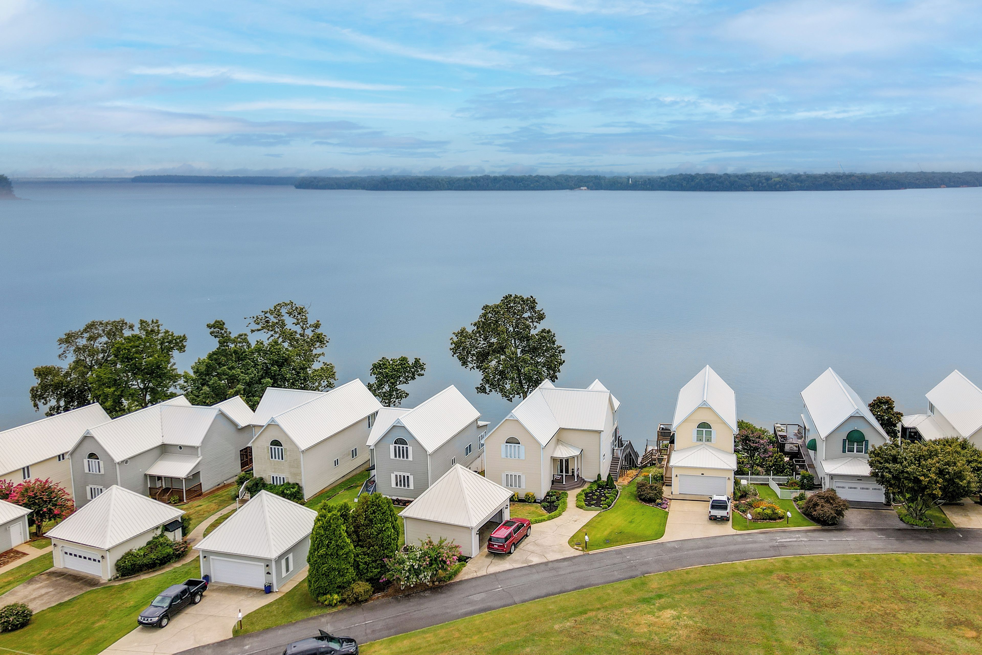 A residential area with houses, a road, and a body of water in the background.