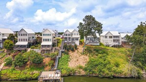 Une propriété située au bord de l’eau, comprenant plusieurs maisons blanches, un quai et un escalier menant aux maisons.