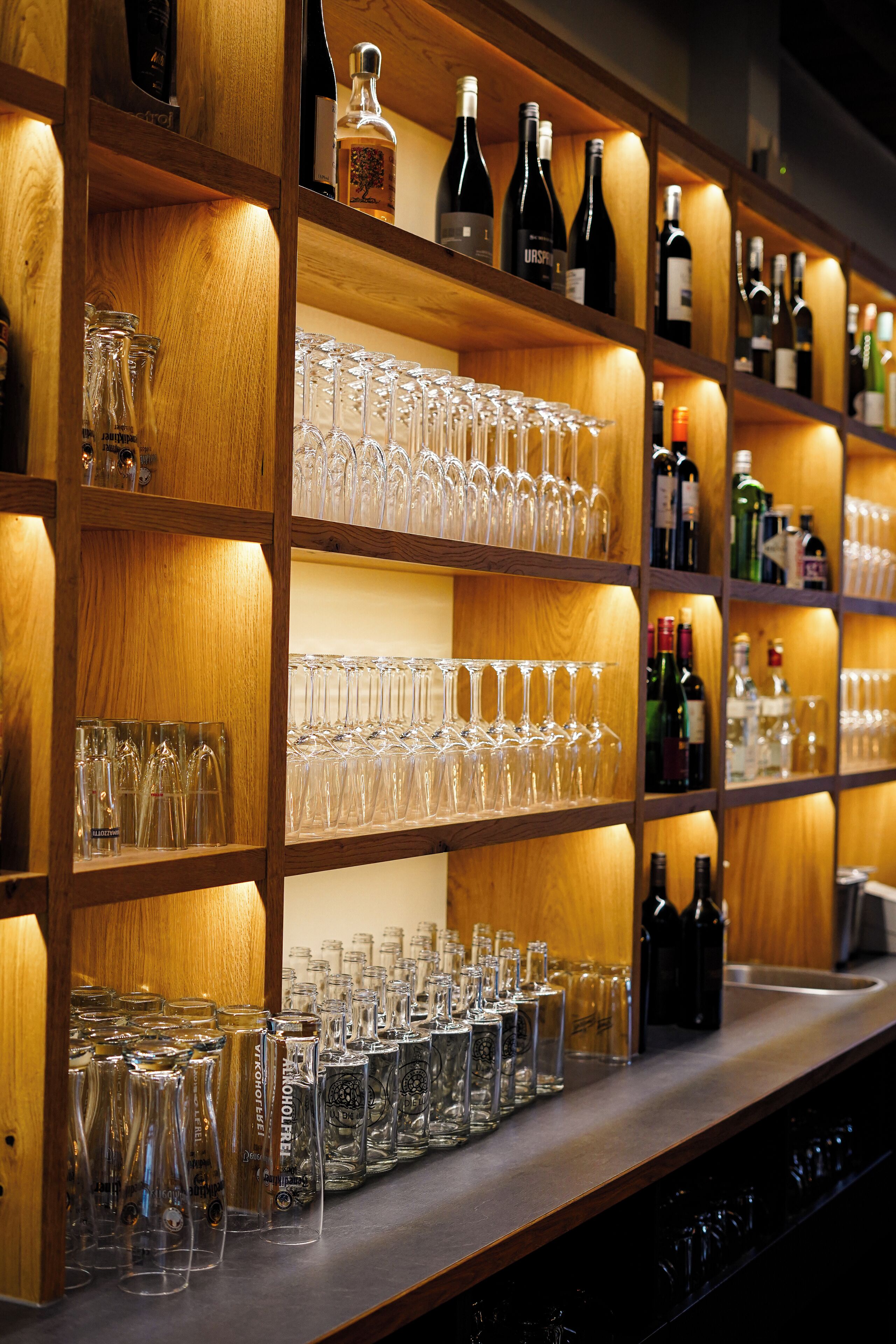 A bar area with shelves of wine bottles and glasses.