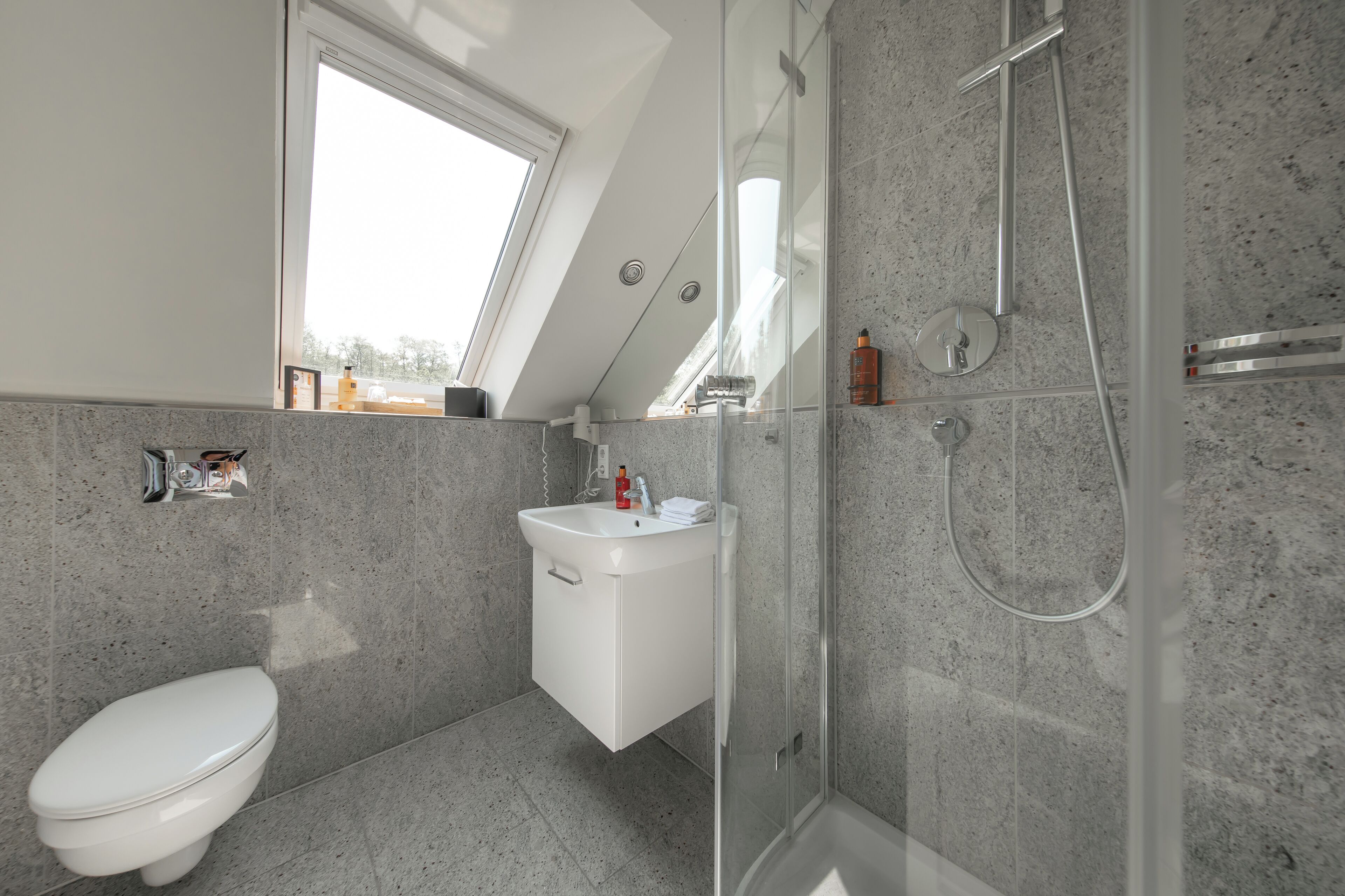 Een moderne badkamer met dakraam, douche en toilet.