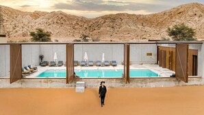 A desert resort with a pool, lounge chairs, and a view of the mountains. - Al Faya Retreat by Sharjah Collection (Al Madam)
