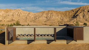 A modern building with a flat roof and a series of lounge chairs arranged in rows. - Al Faya Retreat by Sharjah Collection (Al Madam)
