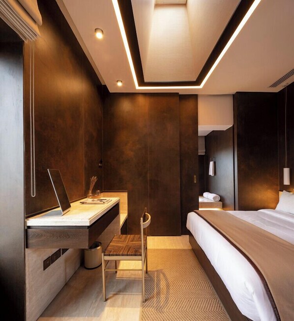 A modern hotel room with a large bed, a desk with a laptop, a chair, and a small table. - Al Faya Sharjah Retreat (Al Madam)