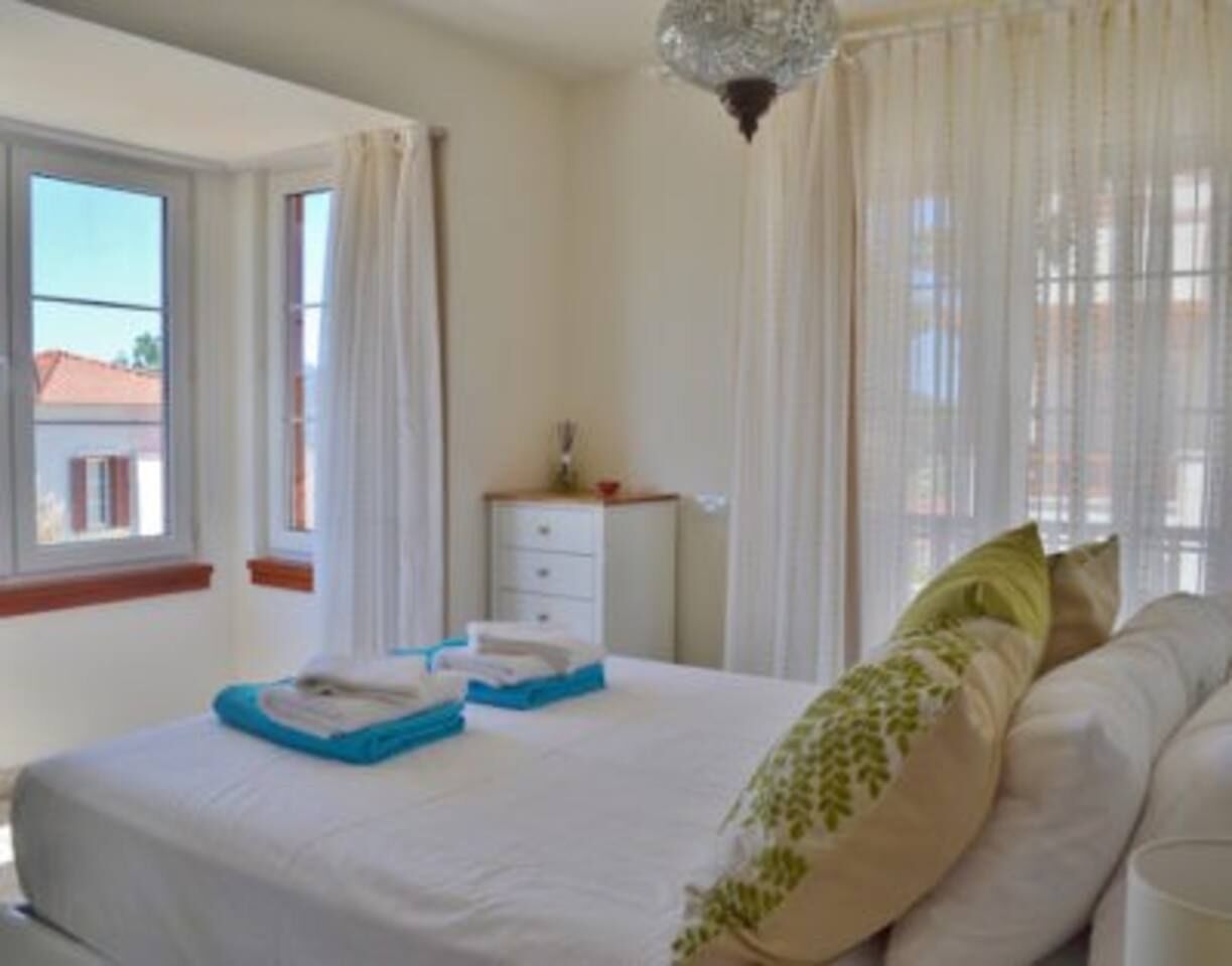A bedroom with a bed, a bedside table, a window, and a curtain.