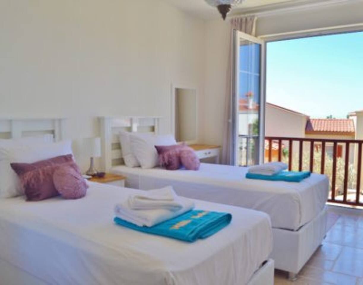 A hotel room with two beds, a balcony, and a view of the outside.