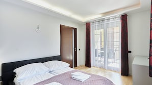 A hotel room with a bed, a door, a window with curtains, and a view of the outside. - Villa Park by Baltic Home (Swinoujscie)