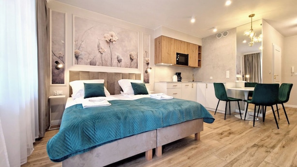A modern bedroom with a large bed, a small kitchenette, and a dining area. - Villa Park by Baltic Home (Swinoujscie)
