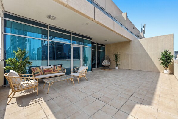 A modern outdoor patio with a sofa, chairs, and potted plants.