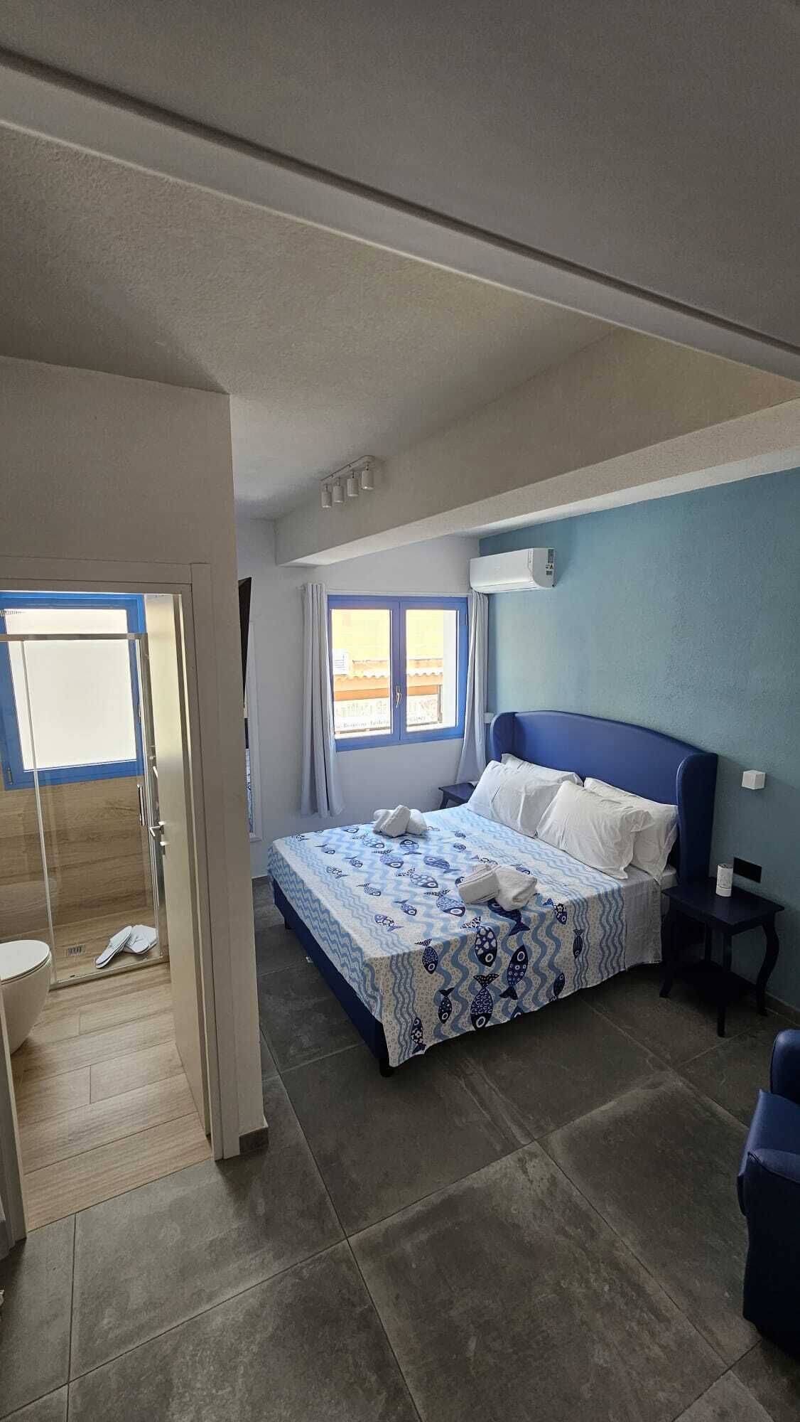 A bedroom with a bed, a window, a bathroom, and a small table.