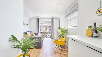 A modern kitchen with a dining area, a yellow rocking chair, and a potted plant.