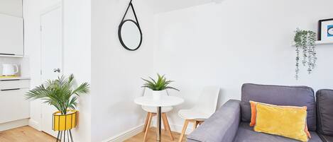 A modern living room with a grey sofa, a white round table, and two potted plants.