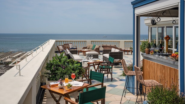 A terrace with outdoor seating, a bar area, and a view of the sea. - Butterfly Beachside Apartment (Viareggio)