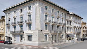 A multi-story building with a classical architectural style, featuring balconies with black railings and a ground-floor entrance with a sign. - Butterfly Beachside Apartment (Viareggio)