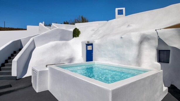 A white-washed building with a blue door, a staircase, and a rectangular pool. - Blue Vice Imerovigli (Santorini)