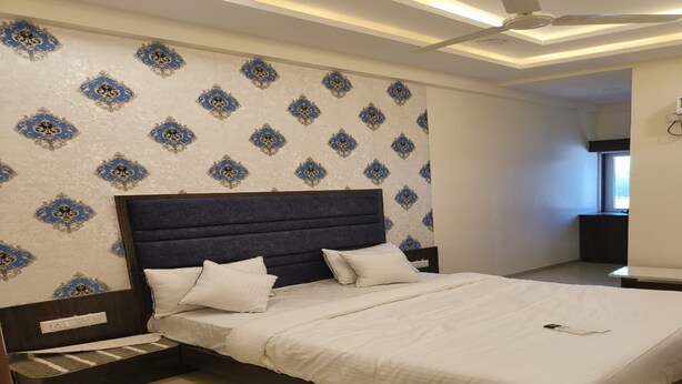Une chambre à coucher avec un grand lit, une tête de lit et un papier peint à motifs.