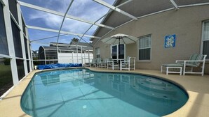 Une piscine intérieure dotée d’un toit en verre, entourée de chaises longues et d’un espace patio.