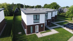 A modern two-story residential building with a flat roof, large windows, and a well-maintained lawn. - Baltic Village - Premiumhaus (Damp)