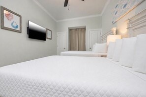 Hotellihuone, jossa on suuri sänky, seinälle asennettu taulutelevisio ja ikkuna, jossa on verhot.