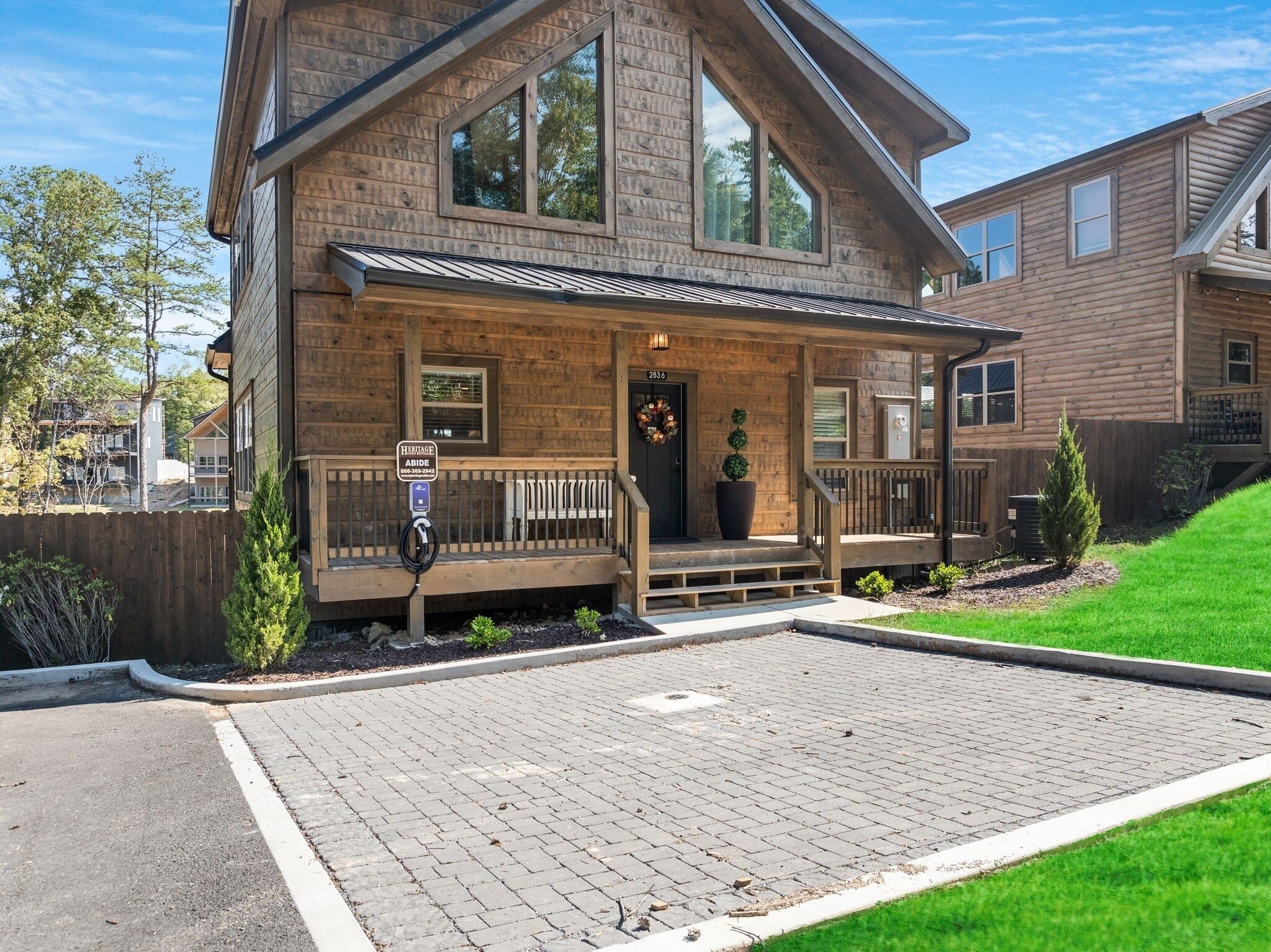 A two-story log cabin with a porch, a garage, and a small front yard.