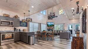 A spacious kitchen with a dining area, wooden floors, and a large chandelier.