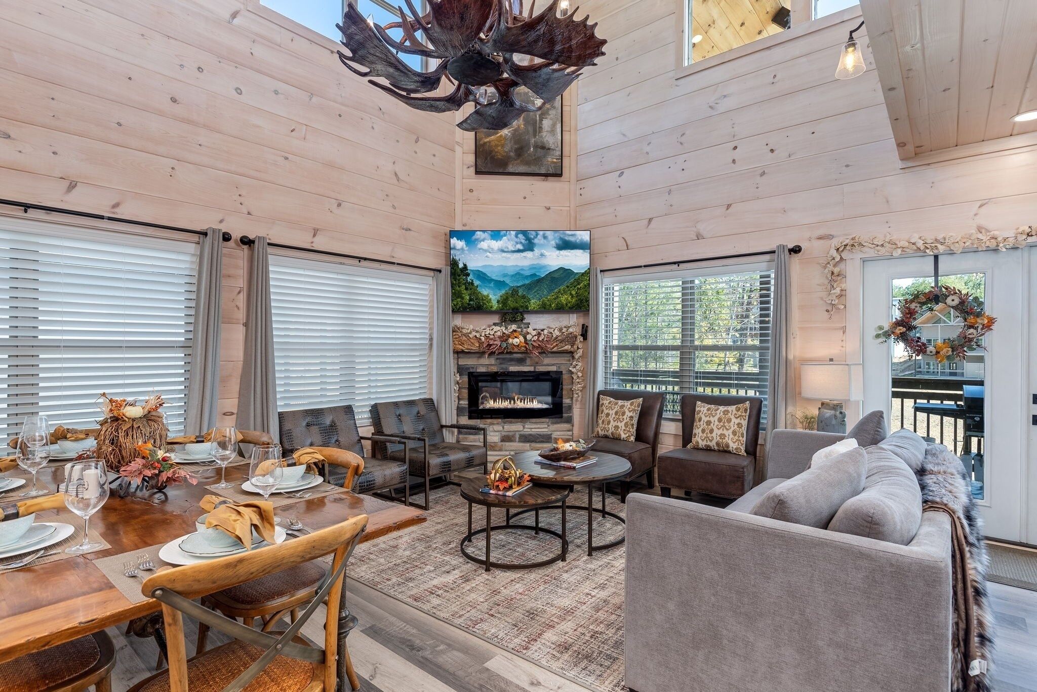 A spacious living area with a fireplace, wooden ceiling, and a dining setup.