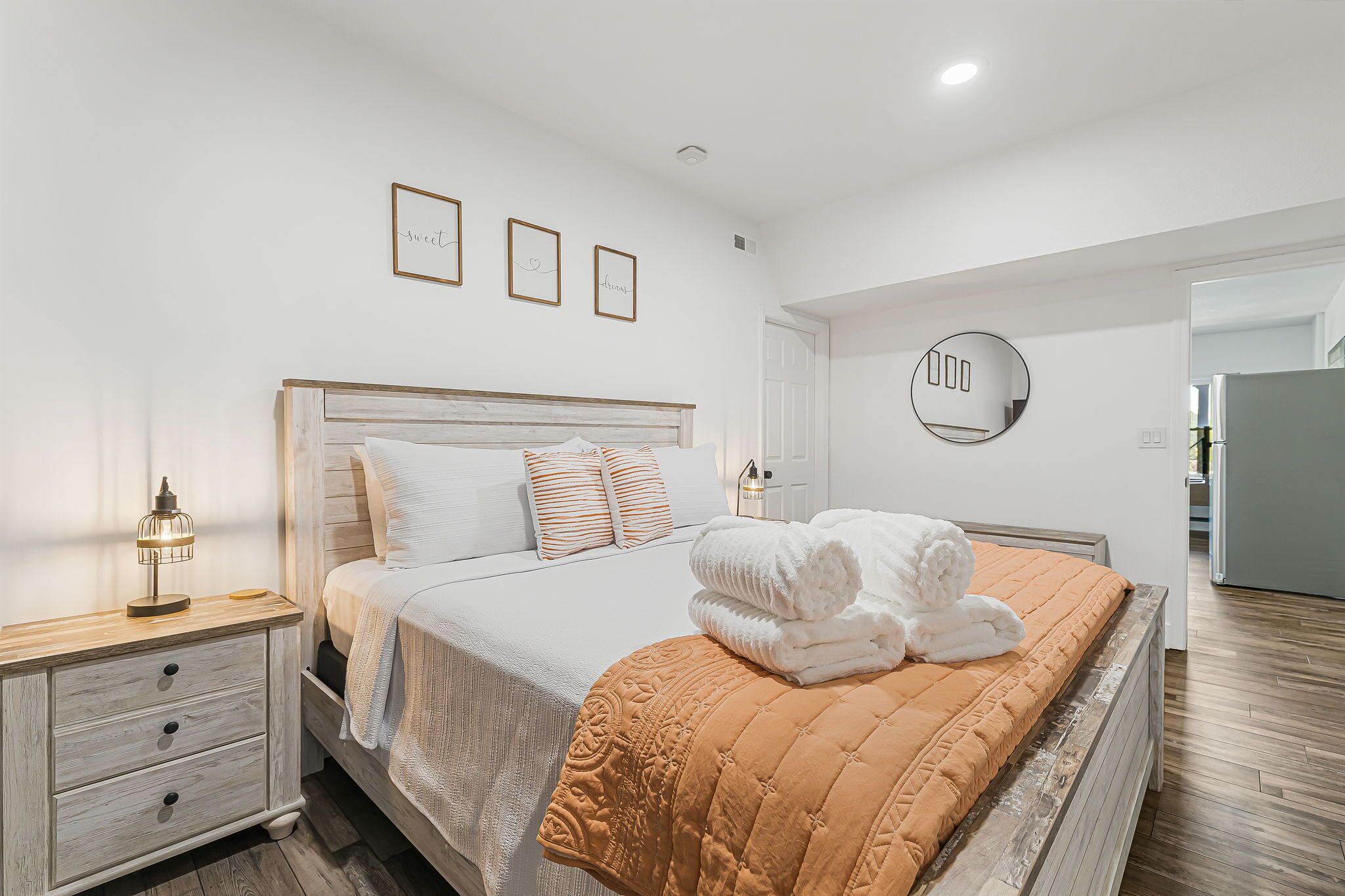 Une chambre bien rangée, avec un lit, des tables de chevet et un miroir fixé au mur.
