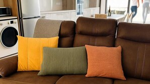 Un sofá marrón con cuatro cojines de distintos colores.