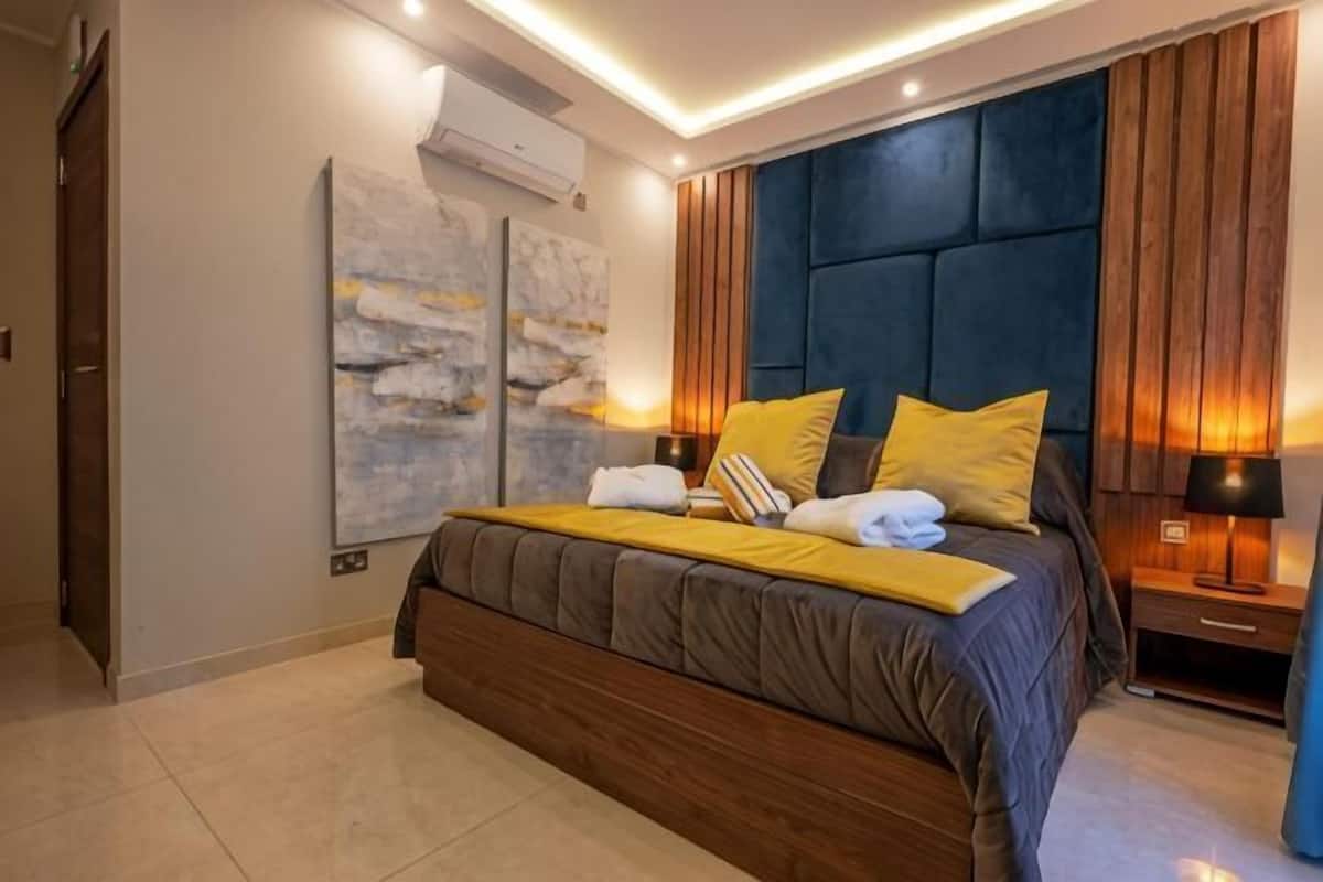 Un dormitorio moderno con una cama grande, lámparas de noche y un aire acondicionado instalado en la pared.