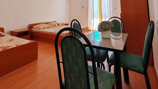 A compact room with a bed, a dining table with chairs, a small table with a potted plant, and a wardrobe. - Studio apartment with Garden view 305 (Neum)