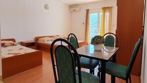 A compact room with two single beds, a dining table with four chairs, and a small potted plant. - Studio apartment with Garden view 305 (Neum)